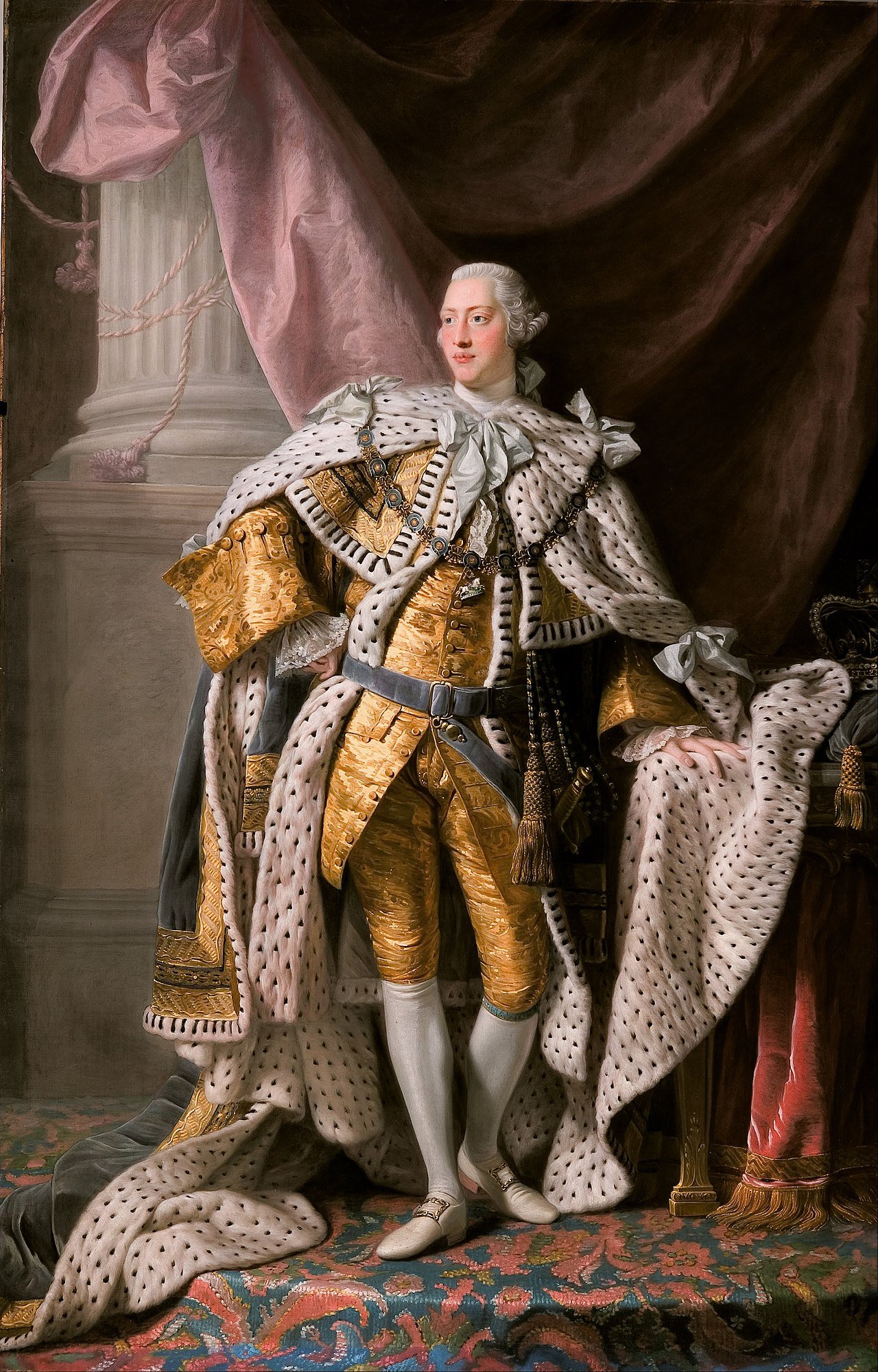 A full-length portrait of King George the Third standing proudly and dressed in clothing for royality that is golden and includes a lavish, flowy robe.