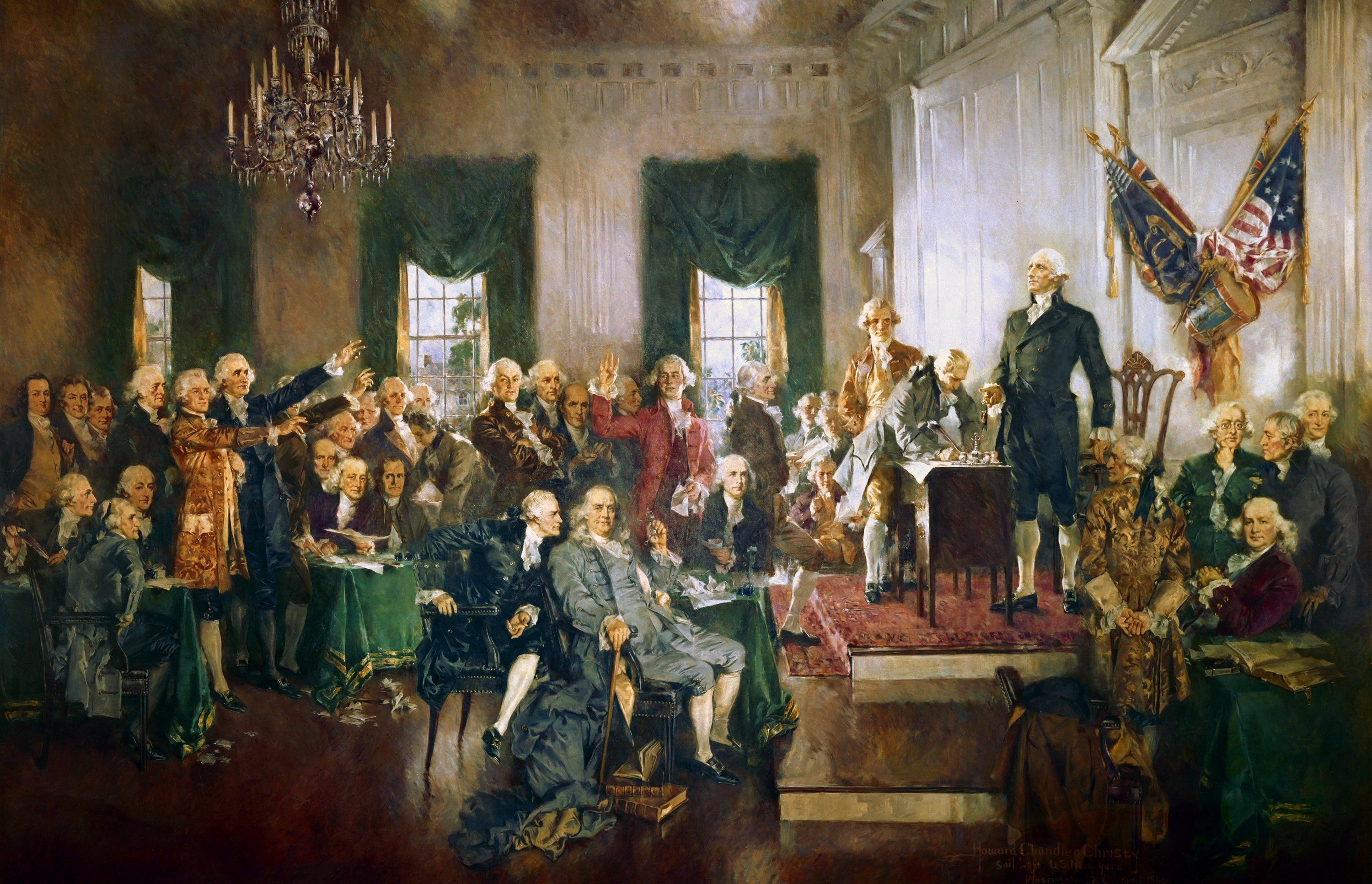 A painting of the delegates gathered in a large state house room where the U.S. Constitution was signed. George Washington is standing on a platform addressing the room. Benjamin Franklin appears prominently seated in the center of the painting.